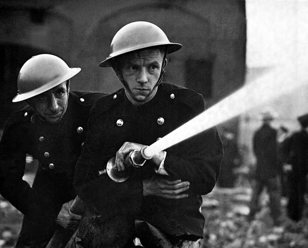 firemen attempt to put out a fire in london after a bombing raid during the blitz